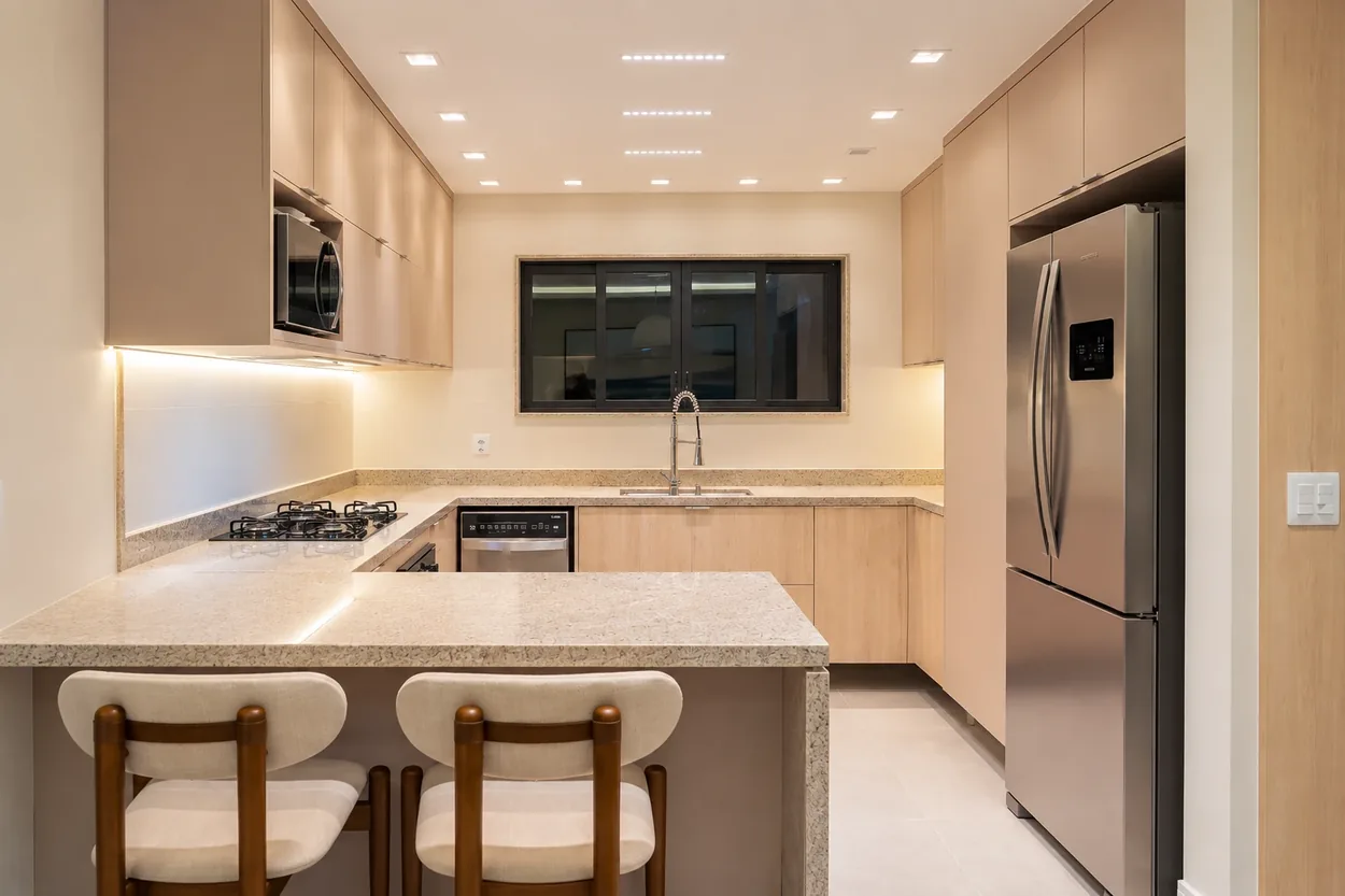 U-shaped custom kitchen with a peninsula counter, upholstered stools and a stainless steel refrigerator