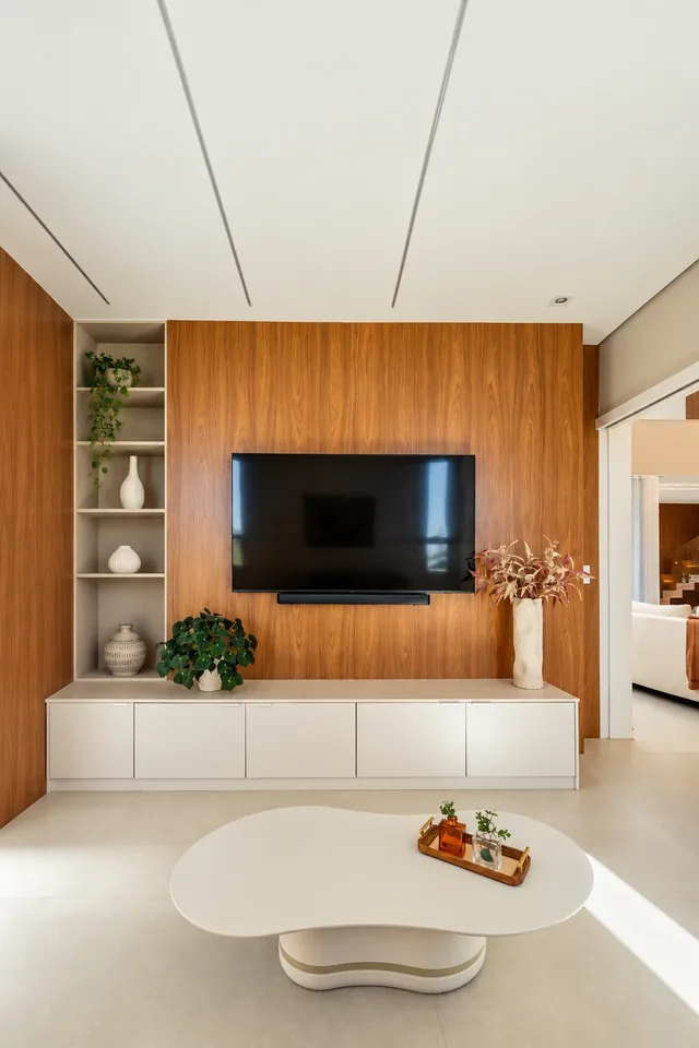 Living room with a wood panel TV wall, a lit display niche and an organic-shaped coffee table